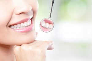 Healthy woman teeth and a dentist mouth mirror with nature green background